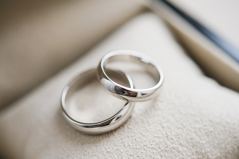 Two silver wedding rings on a cushion